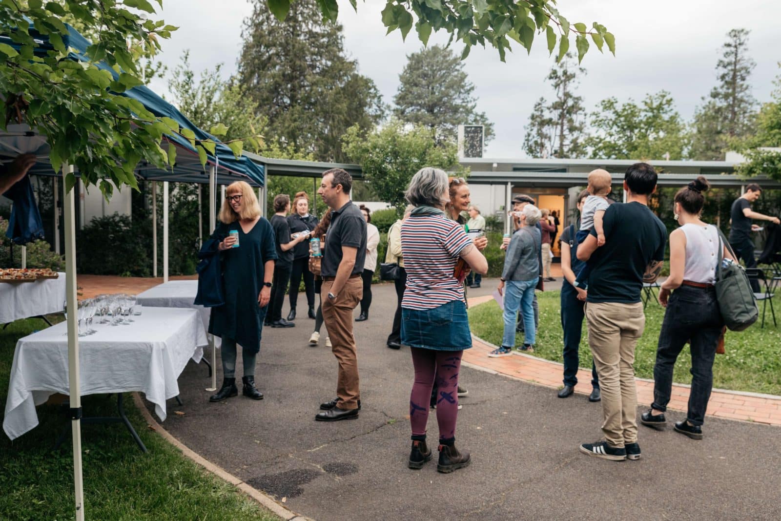 A group of poeple stand outside eating nibbles and drinking champage