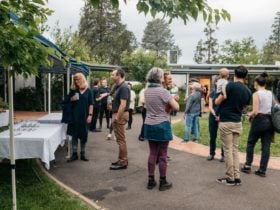 A group of poeple stand outside eating nibbles and drinking champage