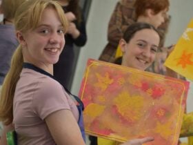 kids holding autumn leaf paintings