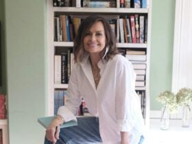 A woman sitting on a stool with a bookcase behind her