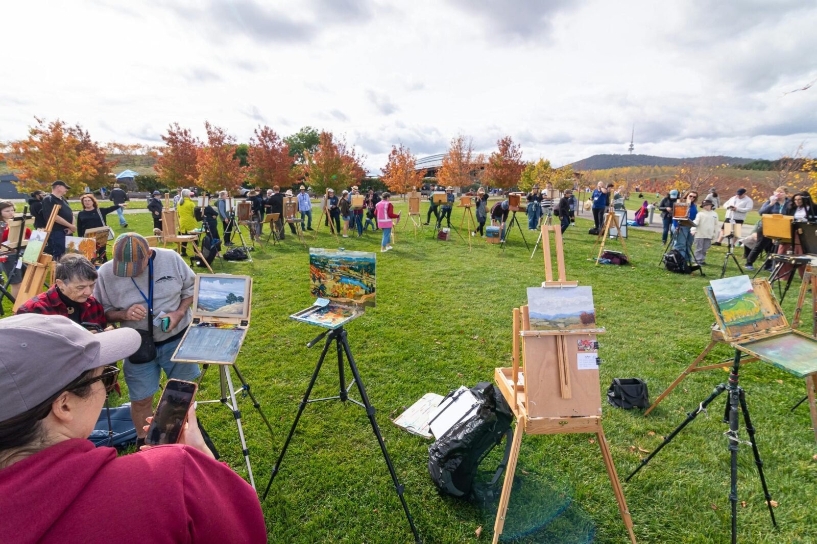 an artists easel with an artwork in front of a view of canberra and lake burley griffin