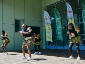 Dancers perform on an outdoor stage with banners saying 