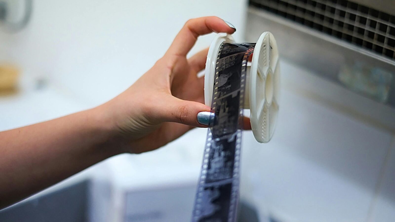 A photograph of a hand taking film off of a film reel