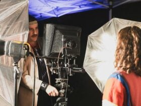 An image of a man setting up a large format camera, surrounded by studio lights