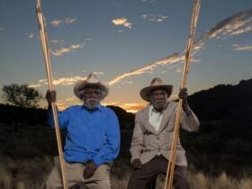 Two first nations elders in sitting in country near Amaroona at sunset with hand carved spears