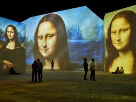 Visitors stand inside an immersive gallery as Mona Lisa projections glow across towering walls.
