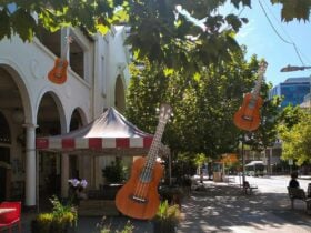 Photo of a building, pavement and gardens with ukeleles