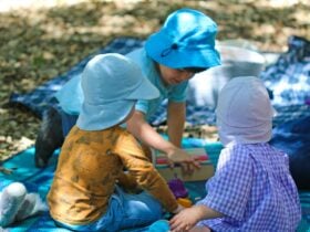 Young children in hats playing on picnic mats