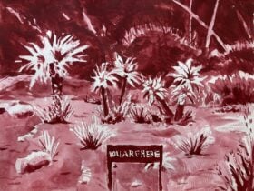 A small sign stands in front of a garden bed of a few white flowers. The sign reads