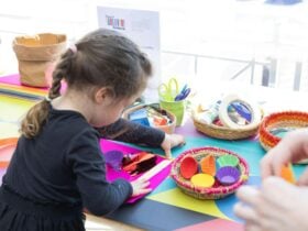A young girl busy at a crafting table with colourful art supplies.