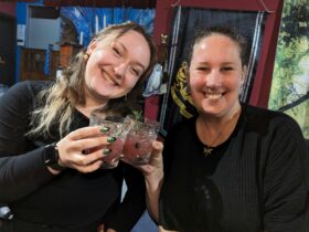 Two women smiling and drinking cocktails they brewed themselves.