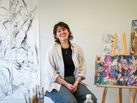 Sarah Murray sitting beside her artworks in her studio.