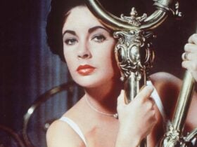 Woman holds onto gold pole looking ominously at camera