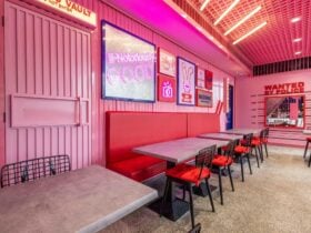 Bright-pink interior decorated with various props. Red booths. (Bad Bunny's interior)