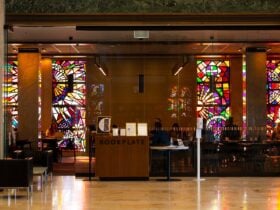The front glass doors of a cafe. There are stained glass windows on the back wall of the cafe.