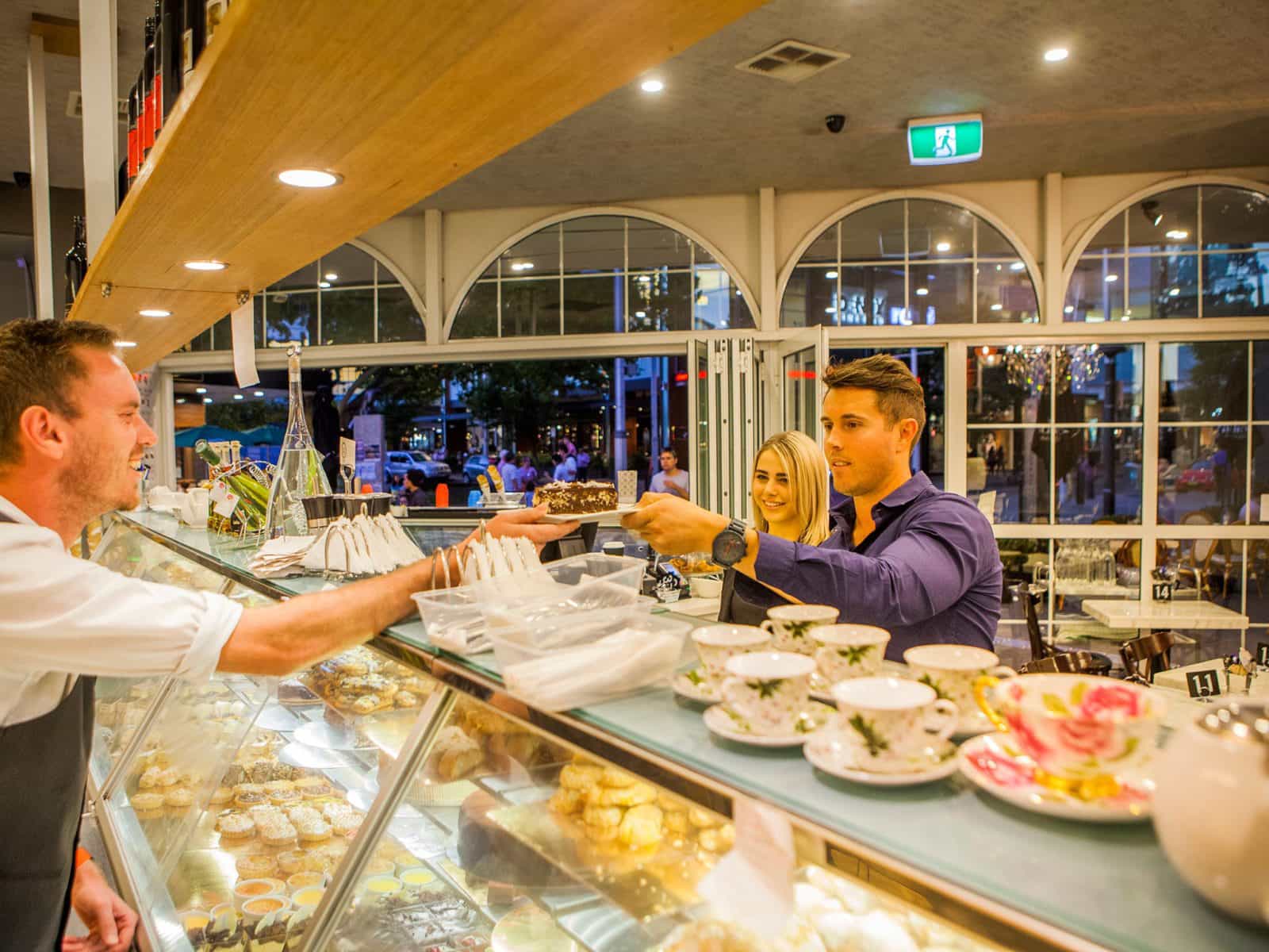 Couple couple being served cake over the counter