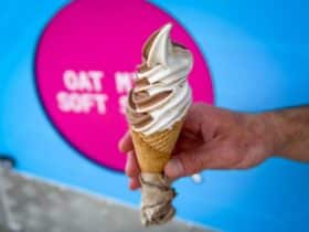 A hand holding a vanilla and chocolate soft serve icecream in a cone