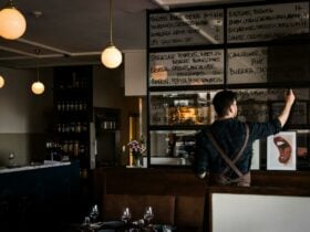 A man writes a menu on a large window glass.