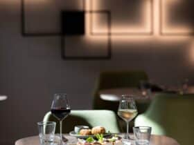 A table of two set for dinner with meals and wine glasses.