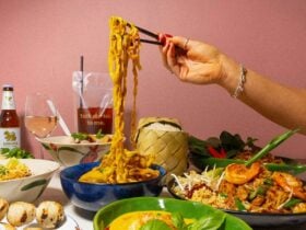 Hand using chopsticks to pick up noodles