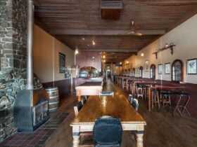 Pot belly woodfire on left-hand wall surrounded by stonework, with seating area and pool table throu