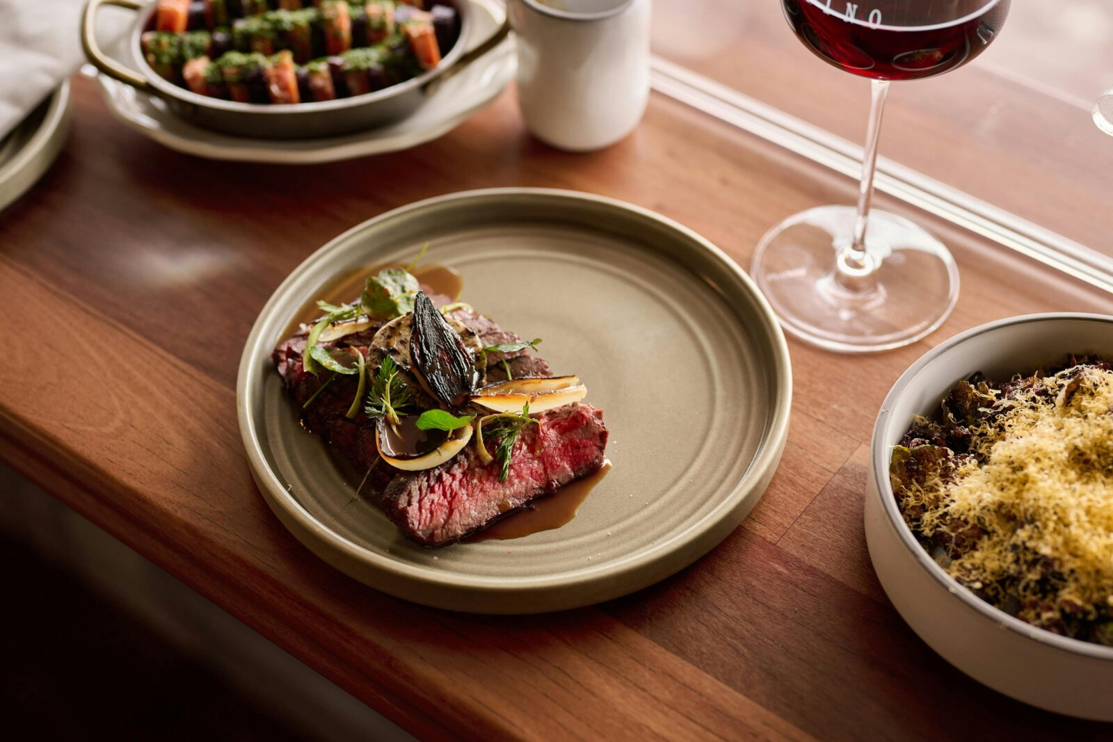 Wagyu flank + garlic butter, served with a glass of red wine, a side of carrots, and sprouts