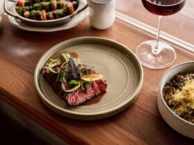 Wagyu flank + garlic butter, served with a glass of red wine, a side of carrots, and sprouts