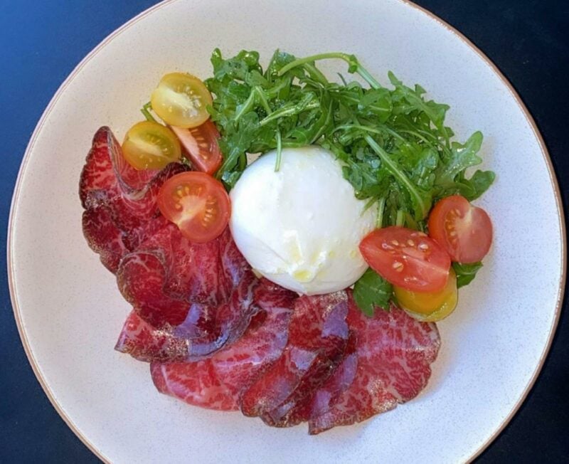 Dish with meat, cheese, tomato and rocket