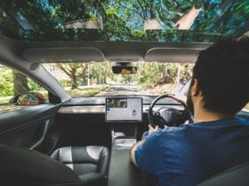 Image take from inside a Tesla from the backseat, view of a the driver from behind