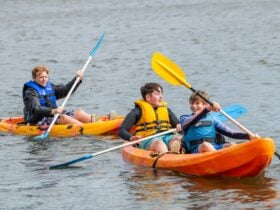 3 Male Youth on Double and Single Kayak in water