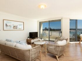 Lounge room with modern rattan lounge, TV and ocean views
