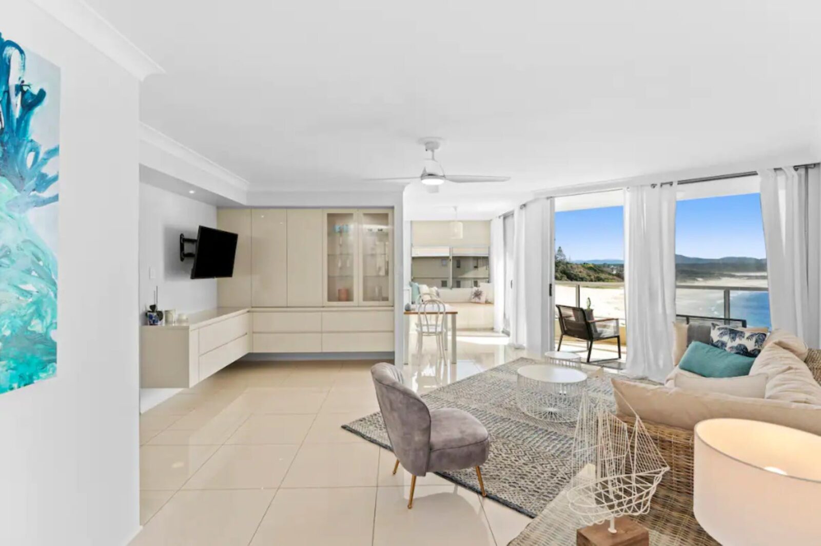 Living room with lounges, ceiling fan, TV and ocean views
