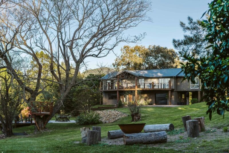 Image of property with firepit area in front view large tree sits to the left as the sun goes down