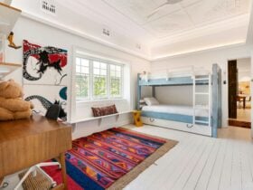 Cozy bedroom with a bunk bed, colorful rug, and artwork on the wall.