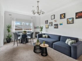 A living room with a dining table, cozy sofa, and framed artwork on the walls.