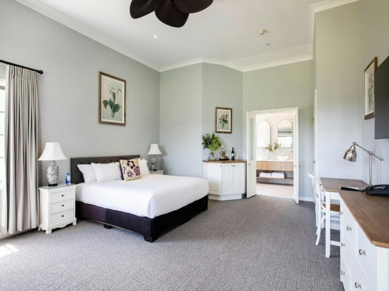 A large bedroom showcasing a bed, a dresser, and a ceiling fan, designed for relaxation and comfort