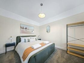 Bedroom with king bed, hanging and shelving area, decor, bedside tables and mirror