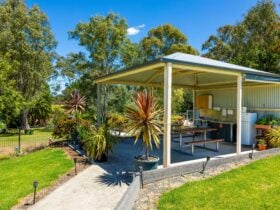 BBQ shelter surrounded by green grass and trees