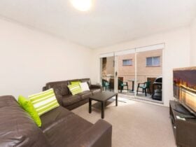 Lounge room with TV, lounges, leading out to balcony