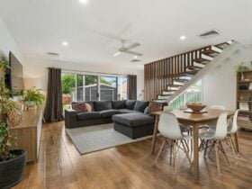 Living area with lounge area, kitchen, stairs and doors to outside