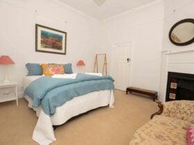 Bedroom with blue bedding, carpet and wood fire