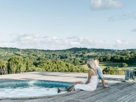 Couple sit on pool deck with their feet in the water gazing out to scenic rural vistas