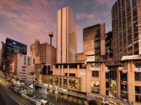 Photo of Hilton Sydney hotel towering over George Street. The Tram passes by out the front.