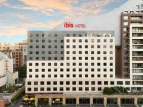 Exterior view of ibis Sydney Darling Harbour hotel building at sunset, surrounded by city apartments