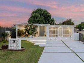 an image of a house facade with a large tree in the backyard and a beautiful pink sunset background