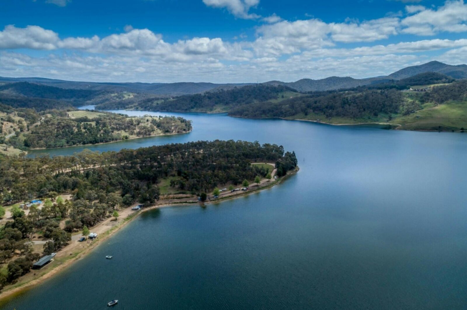 Aerial view over a blue lake and green wooded park along the waters edge