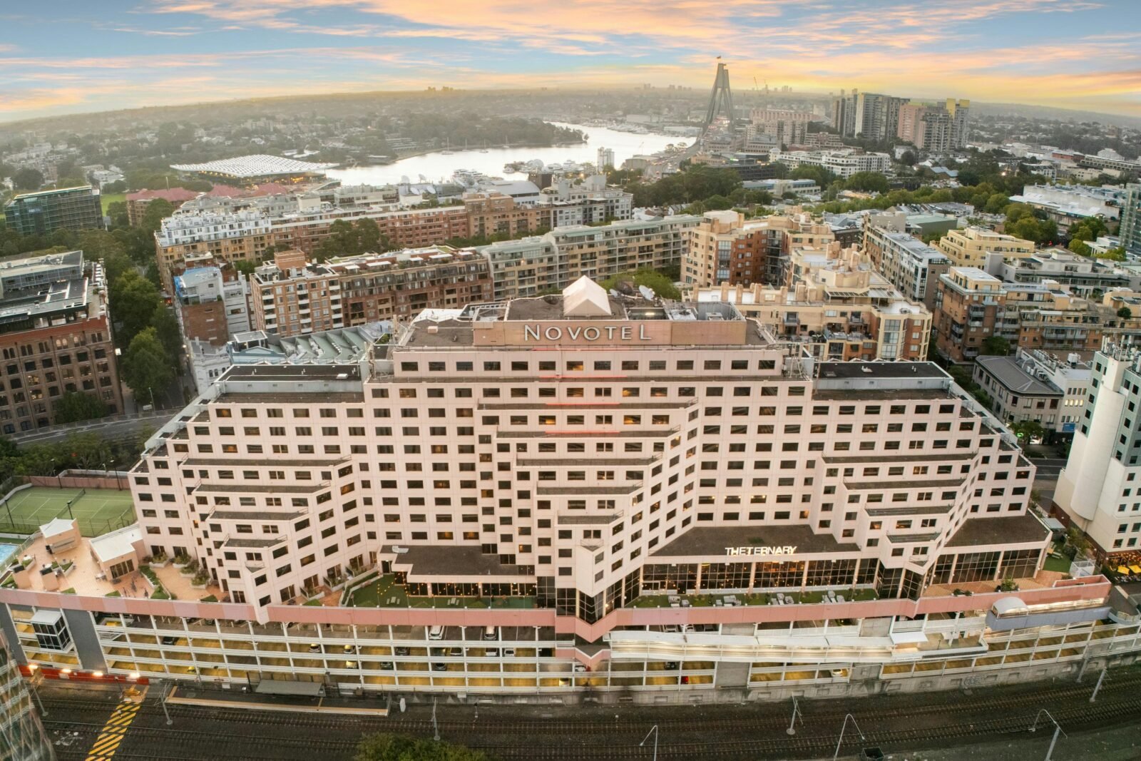 Aerial view of Novotel Sydney on Darling Harbour at sunset, with the hotel building in the foregroun