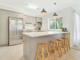 Grey kitchen with fridge, large breakfast/island bench with bar stools
