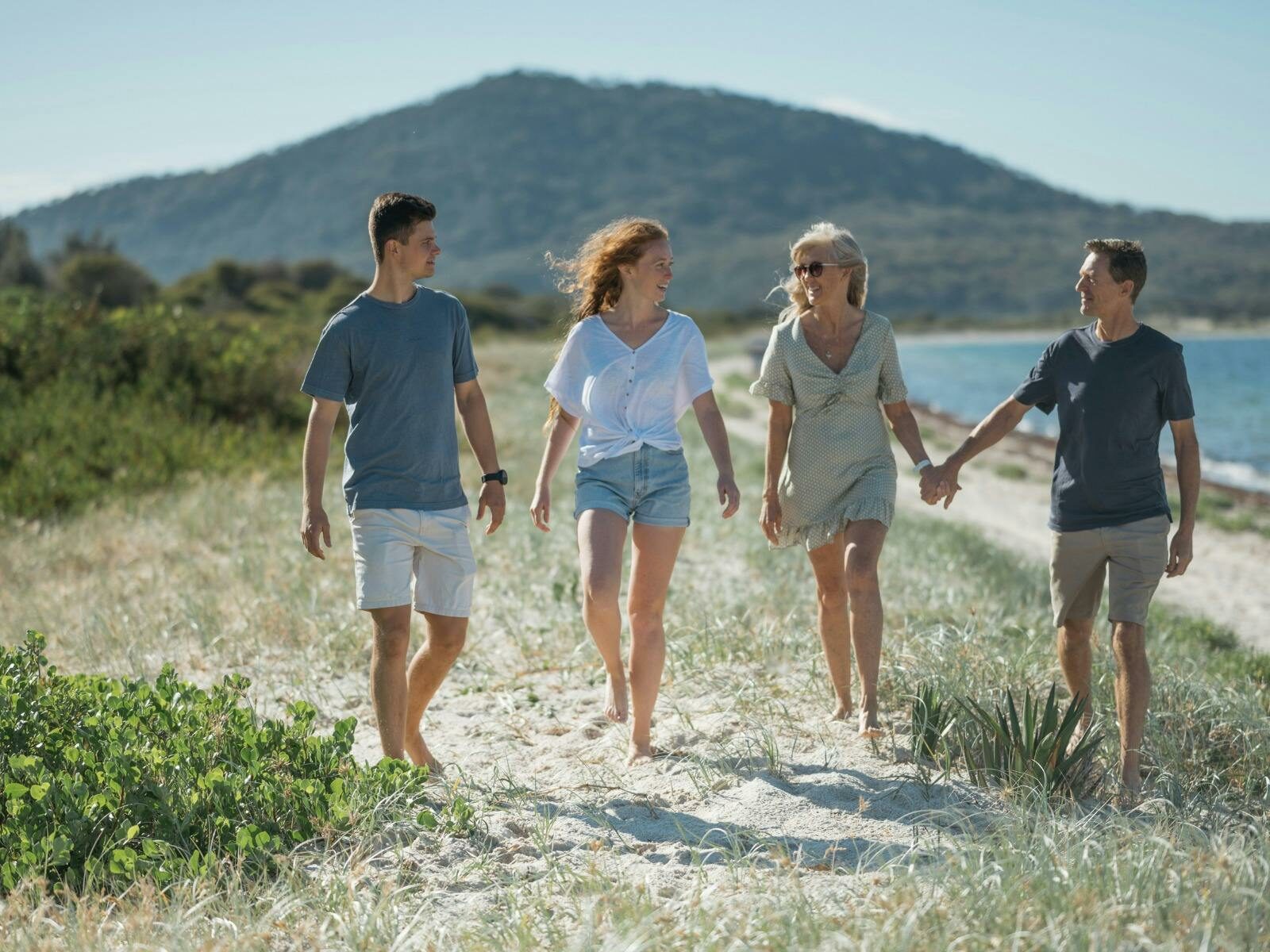 A middle aged and a young couple walking along a beach.