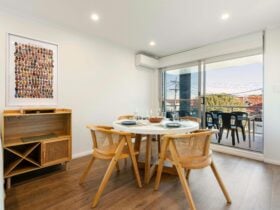 Dining area with a modern table, artwork, and access to an outdoor balcony.